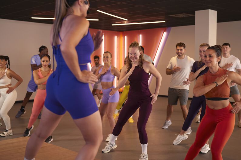 Groupe de personnes participant &agrave; un cours Shape dans un studio de fitness, avec un coach &agrave; l&rsquo;avant.