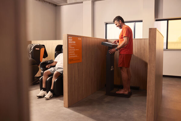 Lid gebruikt de Basic-Fit Body Analyzer om zijn lichaamssamenstelling te meten in de meetruimte van de club.