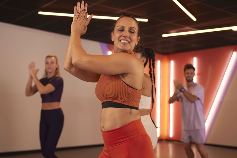 Member enjoying a group dance class in a Basic-Fit studio, moving along with the instructor.