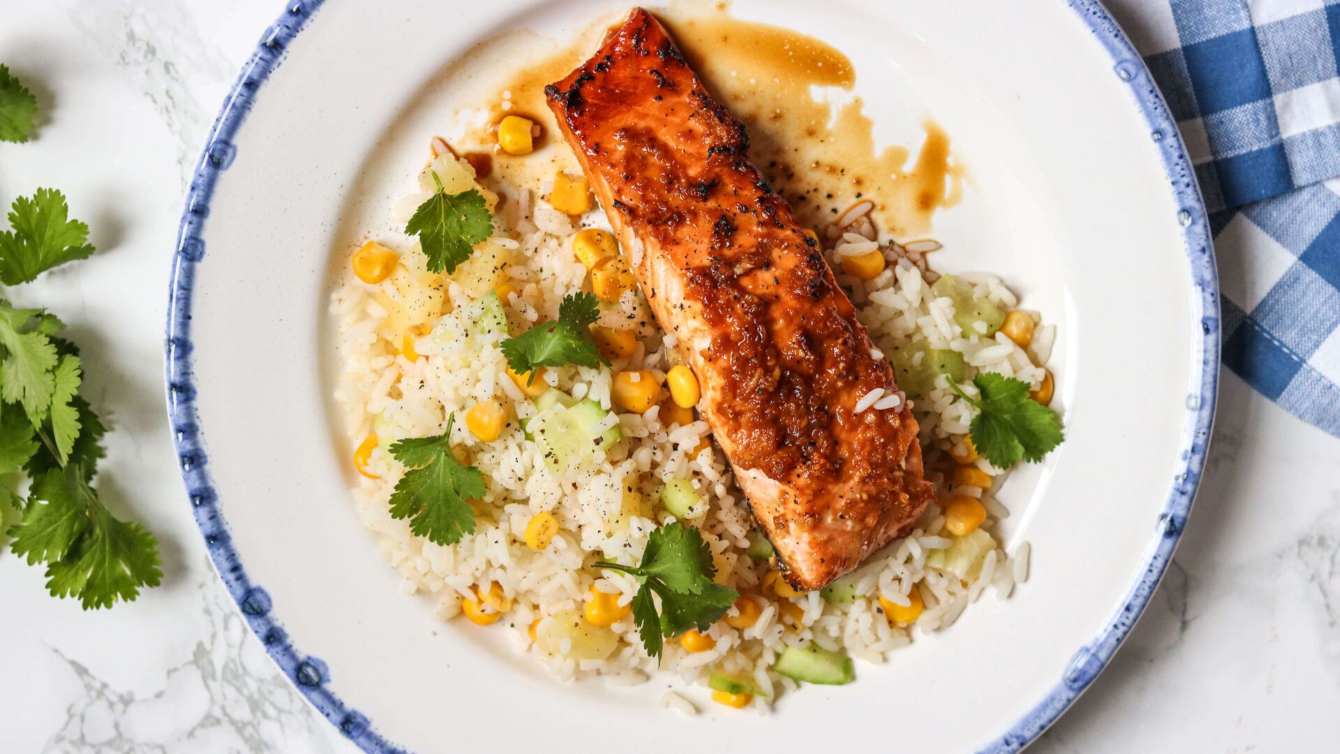 Salmón a la parrilla con arroz, maíz, pepino y cilantro en un plato