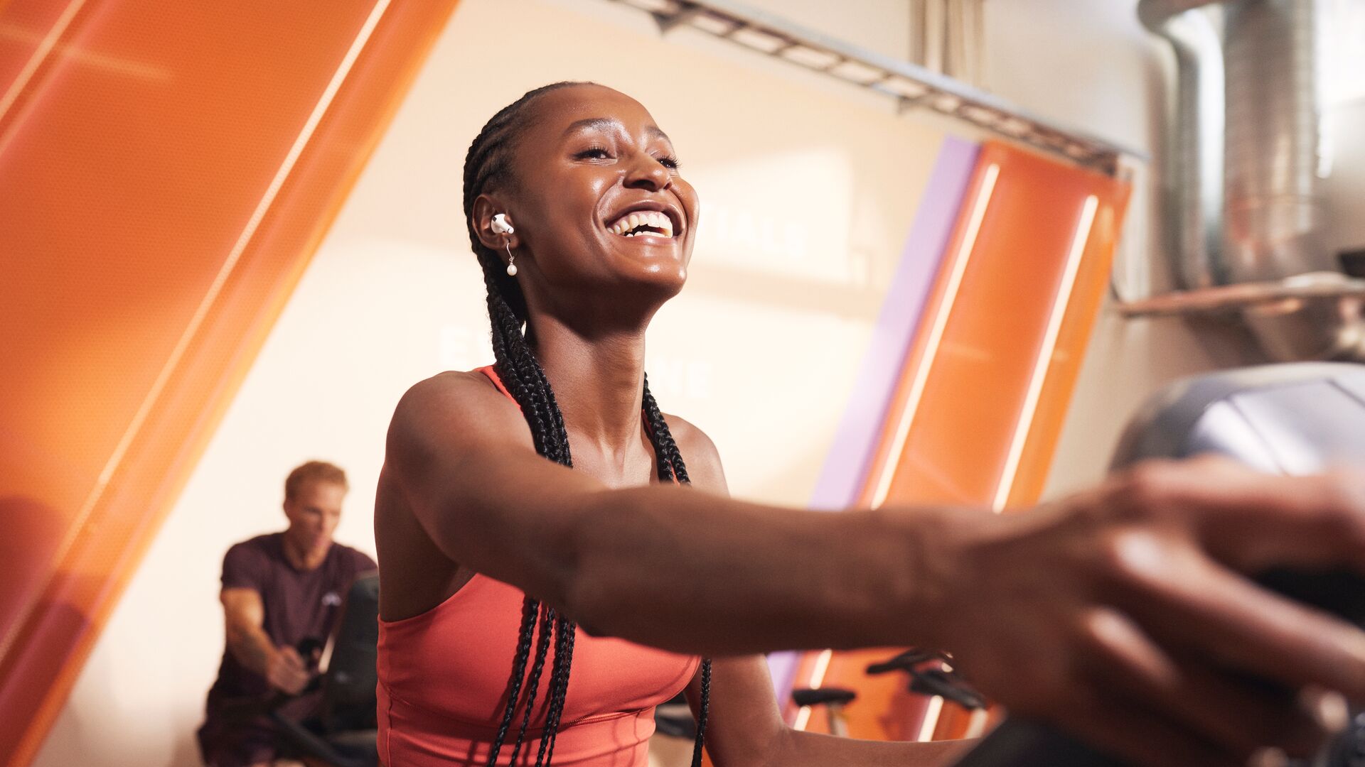 Mujer sonriente entrenando en una elíptica en el gimnasio y manteniéndose motivada