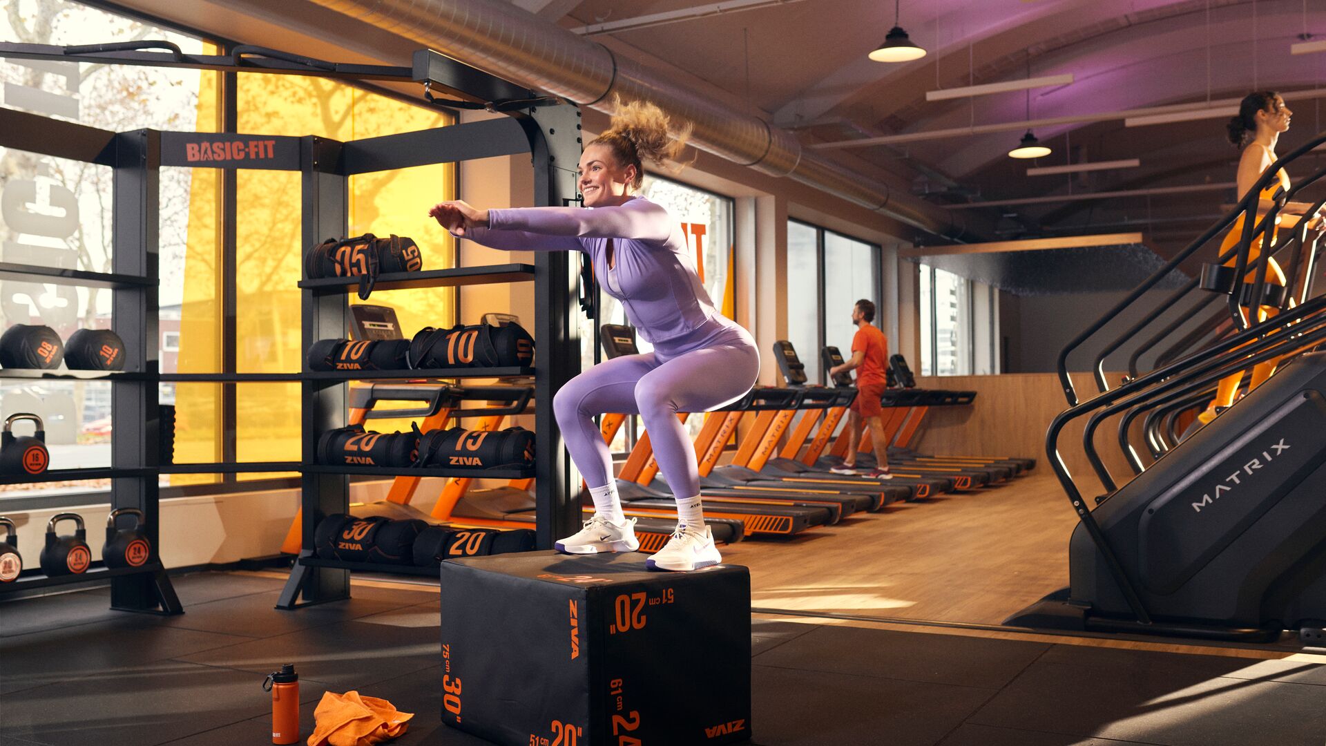 Frau macht einen Box Jump im Functional-Trainingsbereich eines Basic-Fit Clubs