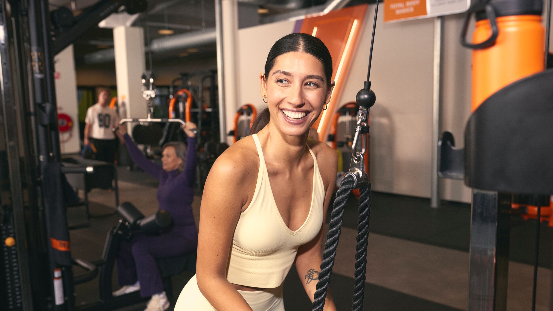 Femme utilisant une machine à câble pour un exercice de triceps dans une salle de sport.