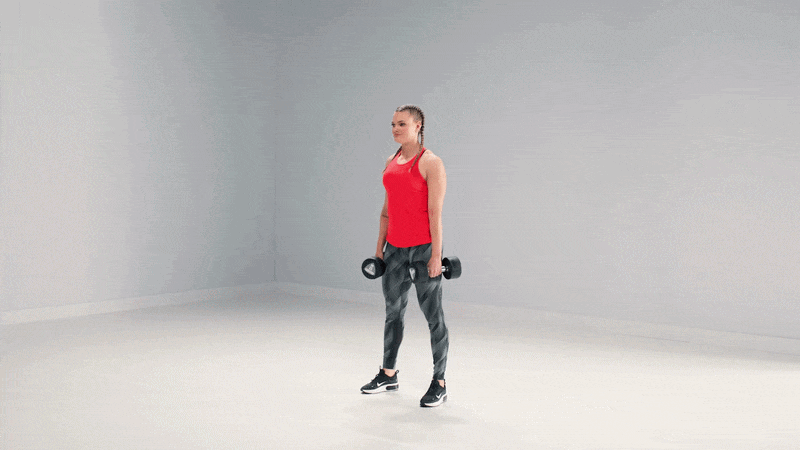Femme réalisant un squat avec des haltères dans un studio