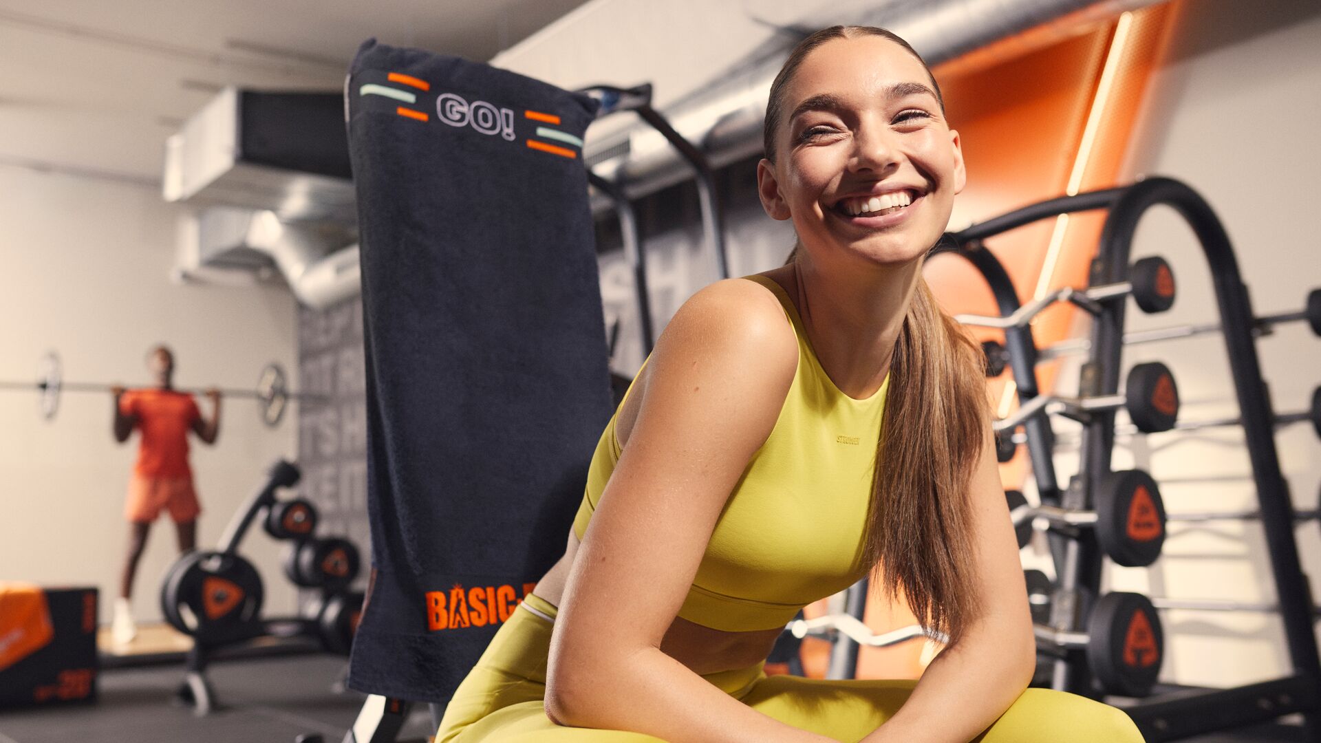 Femme souriante en train de se reposer sur une machine de musculation dans la salle