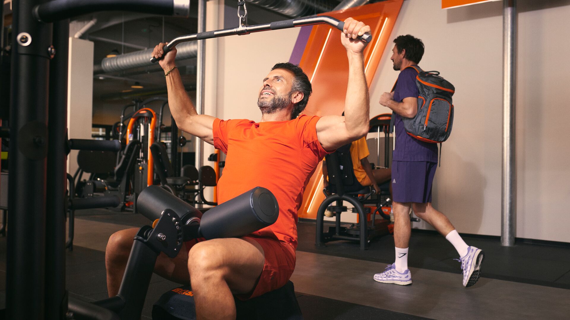 Homme effectuant un tirage vertical sur machine en salle de sport.