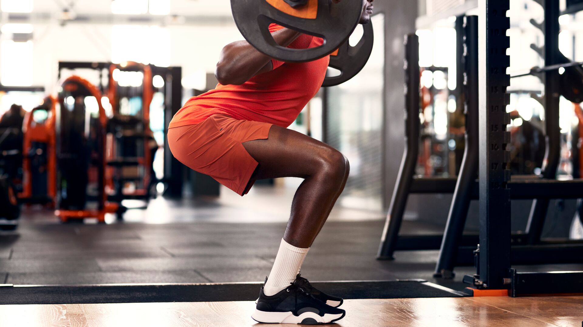 Man voert squats uit met een halter in de sportschool voor sterkere bilspieren